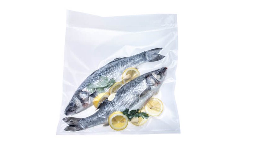 Zavakuumirani ribi z limono v XL vakuumski vrečki na belem ozadju.